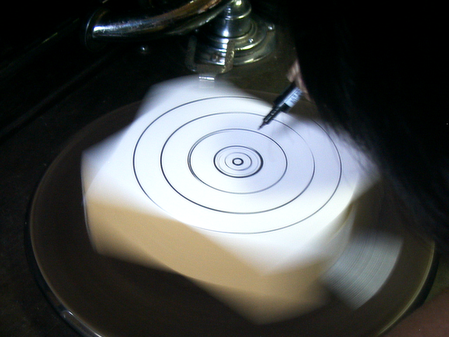 蓄音機のターンテーブルの上に箱を固定して、回転させサインペンで円を描いているところ